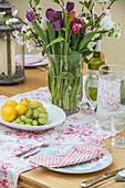 Vase mit Frühlingsblumen und Obst auf einem Tisch in einer umgebauten Scheune in Gloucestershire UK