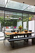 Black leather bench seat at wooden table in conservatory extension of Victorian London townhouse UK
