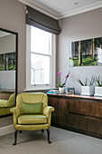 Limonengrüner Sessel und Spiegel mit Anrichte am Fenster in einem Londoner Haus UK