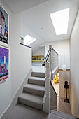 Grey carpeted staircase below skylight with modern art in London home UK