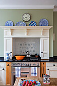 Pfannen auf dem Kochfeld mit Tellern auf einem Regal über dem Einbauherd in einer Küche im Arts-and-Crafts-Stil Sevenoaks Kent UK