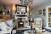 Armchair and sofa at fireside with lit woodburner in Hampshire home