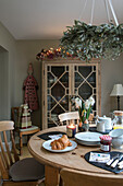 Glass fronted cabinet with croissants on breakfast table in Hampshire home