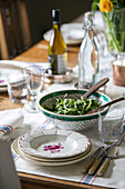 Keramikschüssel und Salat mit Weißwein auf einem Esstisch in einem Bauernhaus in Somerset, UK