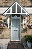 Hanging baskets at porch entrance to Victorian terraced house London UK