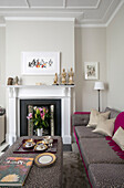 Asian figurines on mantlepiece in living room with grey and pink upholstery in Victorian terrace London UK