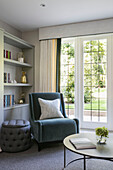 Grey velvet chair and bookcase at window in Surrey home UK