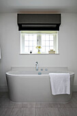 Modern bath below leaded window in Surrey home UK
