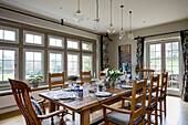 Wooden dining table and chairs with glass pendant shades in West Sussex home UK