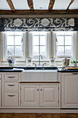 Roman blinds at window with butler sink in kitchen of West Sussex home UK