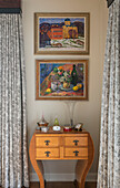 Framed artwork above wooden side table in bedroom of West Sussex home UK