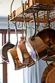 Copper pans hang on rack in Devon kitchen UK