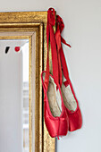 Leuchtend rote Ballettschuhe hängen an einem vergoldeten Spiegel in einem Haus im Norden Londons UK