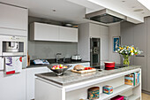 Books and tins on shelving in island unit in modern North London kitchen UK