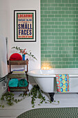 Green tiled bathroom with framed poster and freestanding shelves in Grade II listed Hampshire cottage UK
