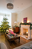 Beleuchtete Kerzen auf einem Tisch mit Weihnachtsbaum in einem Haus in East Dulwich London UK