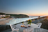 Tulips on terrace table with chairs and view to sea Cornwall UK