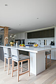 Light grey bar stools in open plan kitchen Hampshire home UK
