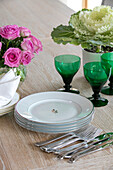 Green glasses and pink roses with plates and cutlery in Hampshire home UK