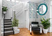 Vintage chair and houseplants in modernised staircase of 1900s Arts and Crafts style London home UK