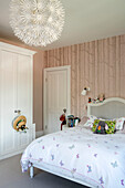 Double bed with sunhat and toys and large pendant shade in girls room of London home UK