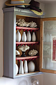 Painted cupboard with vases and coral in Norfolk cottage England UK
