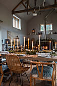 Laub und Kerzenständer auf einem Tisch in einer Scheune mit doppelter Wandhöhe in Shaded White Norfolk England UK