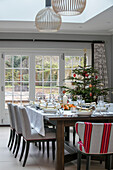 Gedeckter Esstisch für das Weihnachtsessen mit Baum in einem Anbau in Hampshire UK