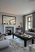 Mirror above classic chrome fireplace in living room of Hampshire home UK