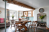 Wooden table and chairs under timber beamed ceiling with structural support in Kent cottage UK