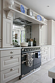 Casserole dish on oven hob with shelf and mirrored splashback in Sussex home UK