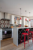 Rote Barhocker an der Frühstücksbar/Weinregal in der Küche eines Londoner Einfamilienhauses UK