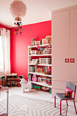 Wardrobe and chair with toys and books on shelves in playroom of London home UK