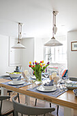 White pendant lights above dining table with tulips in Grade II listed cottage Cornwall UK