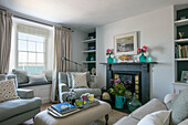 Coloured glass vases and matching armchairs in living room of Grade II listed cottage Cornwall UK