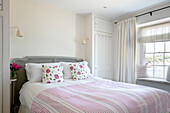 Floral cushions on double bed in Grade II listed cottage with sea view Cornwall UK