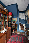 Antikes Bücherregal und Teppich im blauen Flur eines Hauses in Sussex