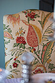 Chair backed in floral textile at dining table in Sussex home