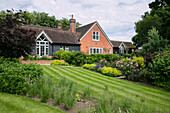 Summer garden and lawn of 1900s former coach house West Sussex England UK