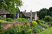 Summer borders and brick wall with weatherboard exterior of former Victorian coach house West Sussex England UK
