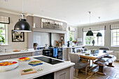 Open plan kitchen with table and black pendant shades in former Victorian coach house West Sussex UK
