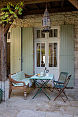Light green shutters with table and chairs in courtyard of Issigeac townhouse Perigord France