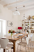 White pendant light and chairs at wooden table with shelving in Issigeac townhouse Perigord France