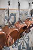 Copper saucepans hanging on metal hooks in Issigeac kitchen Perigord France