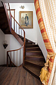 Striped gold door curtains and wooden staircase with framed portrait in Issigeac townhouse Perigord France