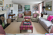 Beige armchairs and tartan ottoman in light grey Hampshire living room England UK