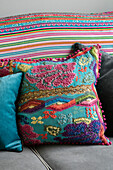 Tapestry cushion and striped blanket on grey sofa in Hampshire home England UK