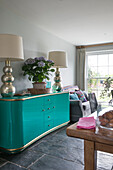 Large lamps on turquoise sideboard in Hampshire home England UK