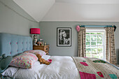 Pinke Nachttischlampe mit geknöpftem Kopfteil und gestrickter Decke im Mädchenzimmer in Hampshire, England, UK