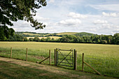 Metalltor und Zaun mit Blick auf die Landschaft von Hampshire England UK